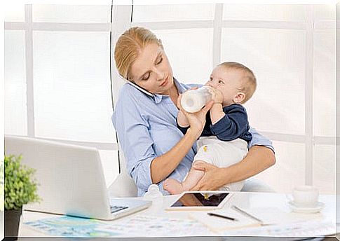 mother working, giving her child bottle and talking on mobile