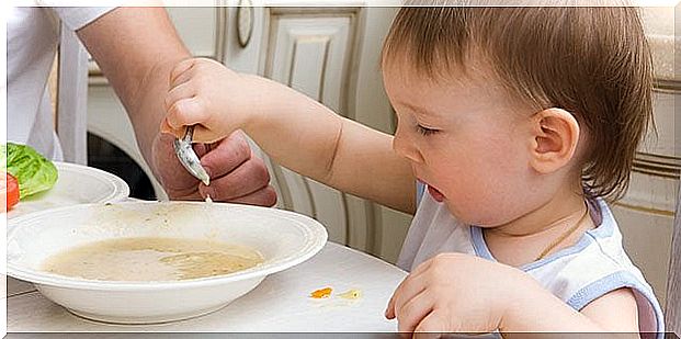 small child eating soup with a spoon himself