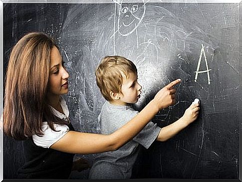 teacher helping child write on blackboard