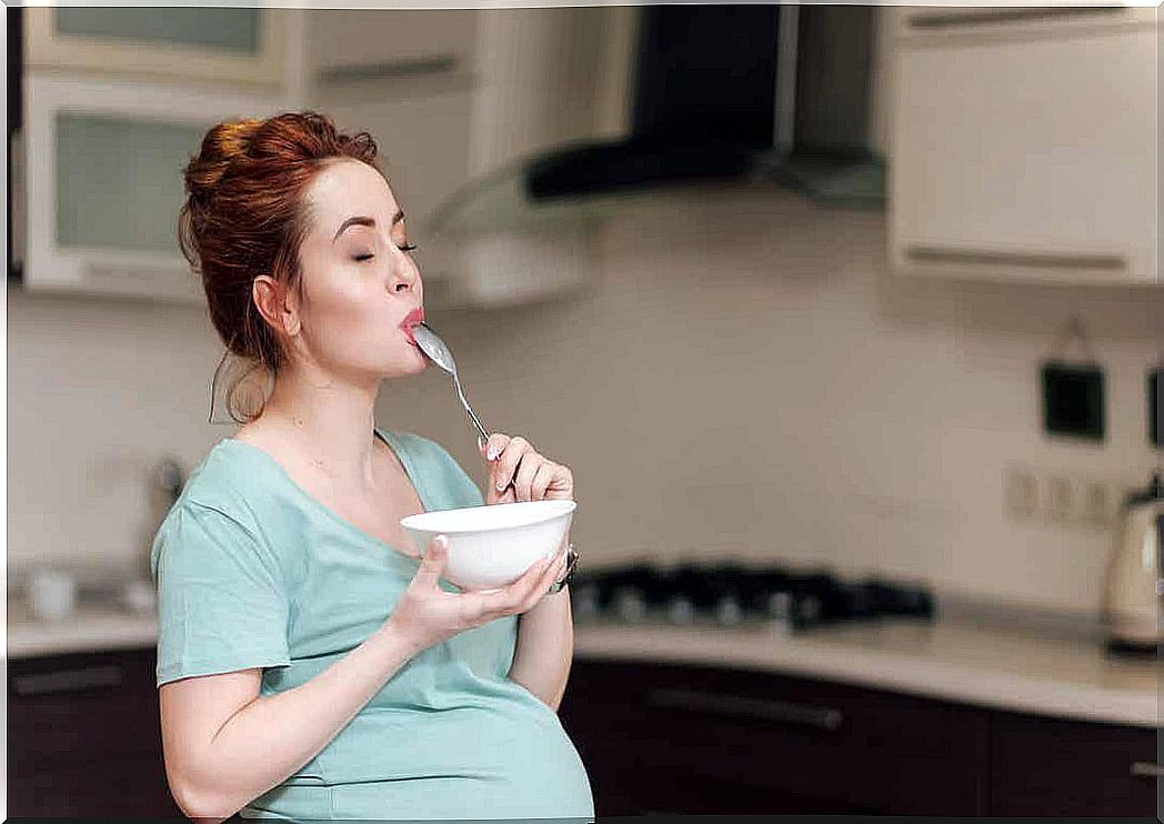 A pregnant woman enjoys a bowl of yogurt