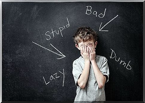 boy standing up at blackboard with condescending words