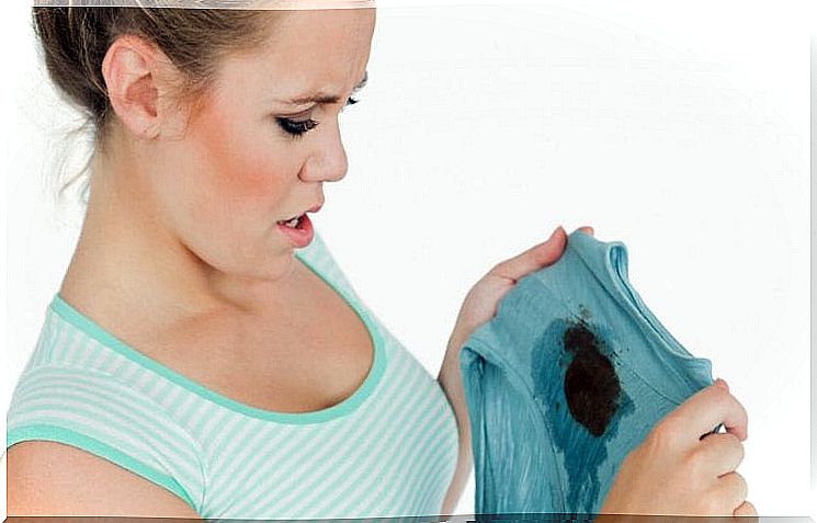 woman looking at piece of clothing with large stain