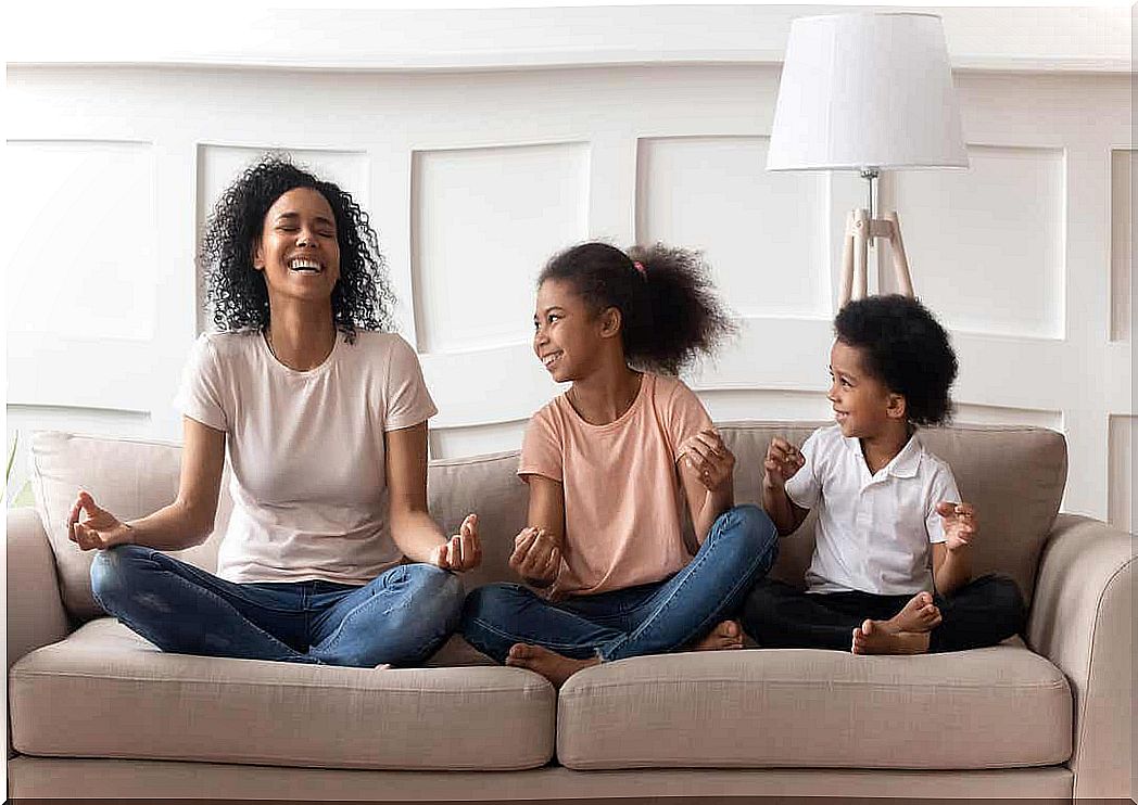 A mother meditates on the couch with her young daughter and son