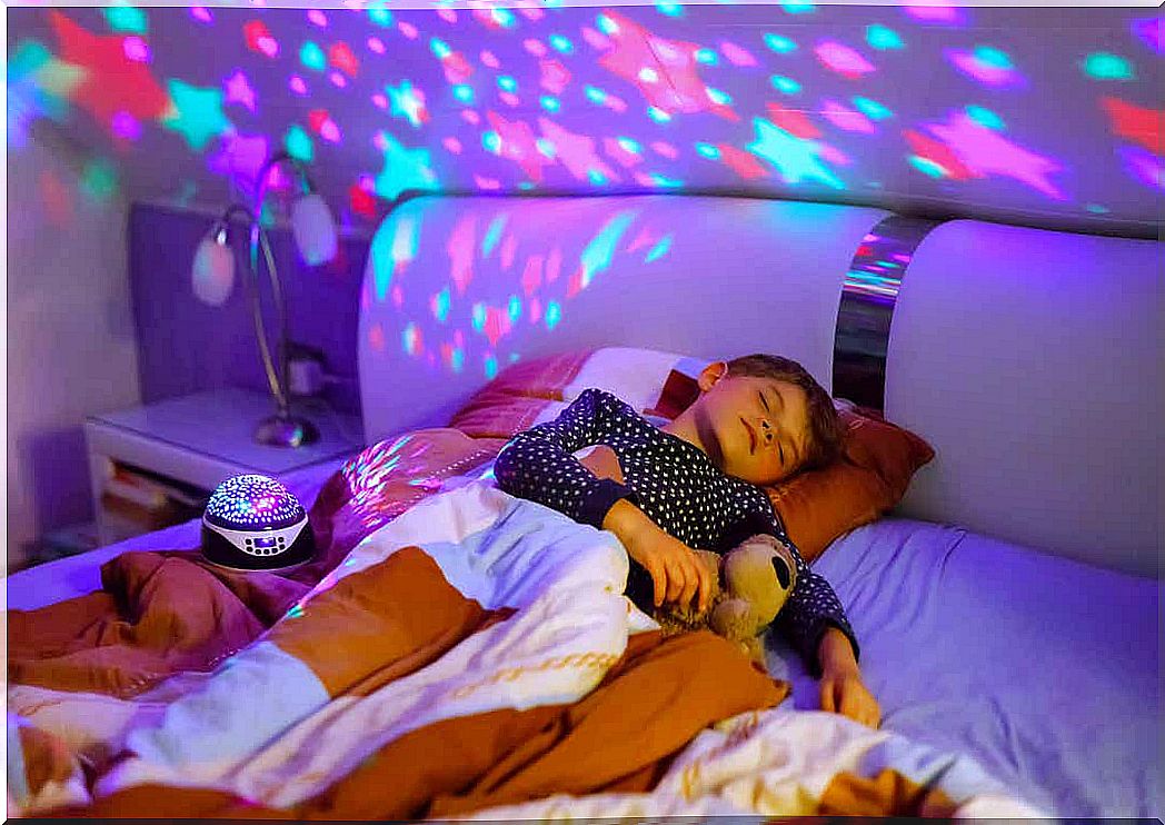 A child sleeps next to a star projector