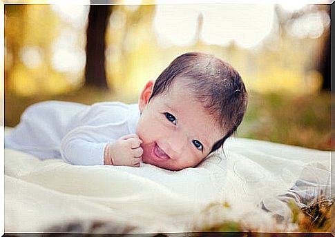 little baby lying on blanket outside and smiling