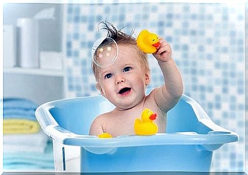 Baby playing with yellow bath ducks in the bathtub 