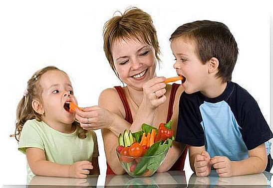 mother feeding children vegetables